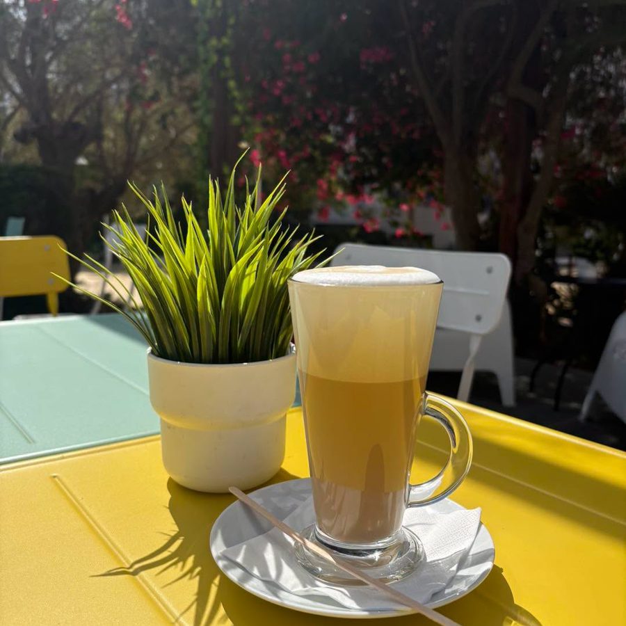Latte on a yellow table with bougainvillea behind