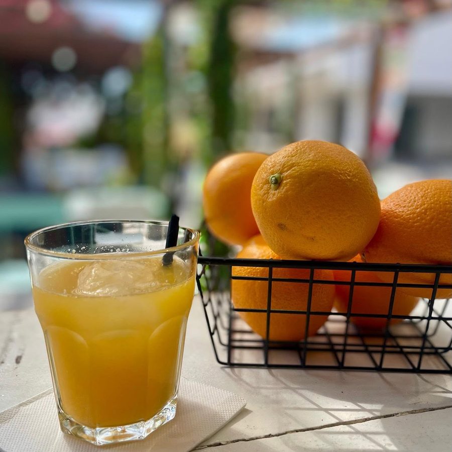 Fresh orange juice beside a basket of oranges